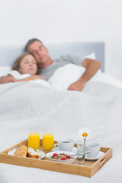 Peaceful couple sleeping with breakfast tray on bed — Stock Photo, Image