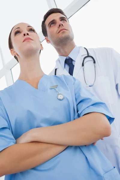 Serious doctor and surgeon looking away — Stock Photo, Image