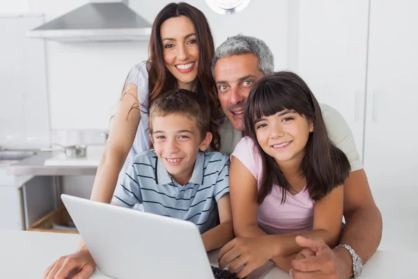 Lycklig familj sitter i köket med sin laptop — Stockfoto