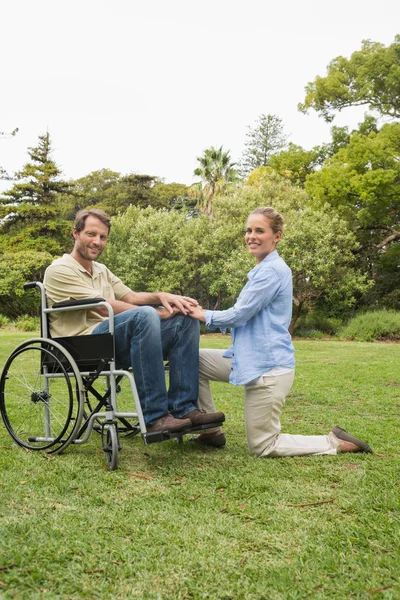 Homem atraente em cadeira de rodas com parceiro ajoelhado ao lado dele — Fotografia de Stock