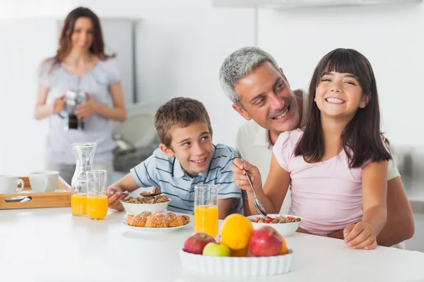 Smiling family eating breakfast in kitchen together — Stock Photo, Image