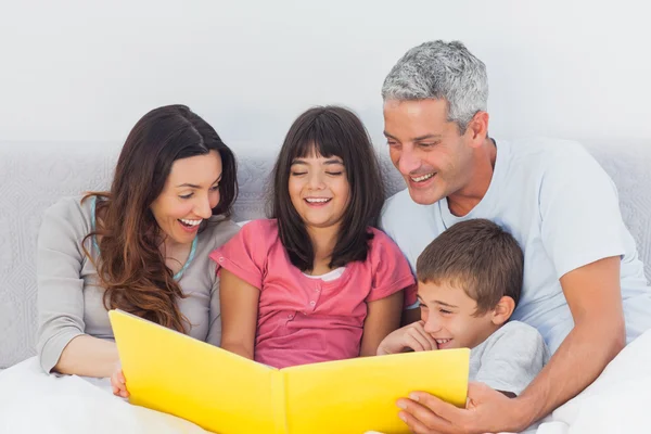 Family looking together at their photograph album in bed — Stock Photo, Image
