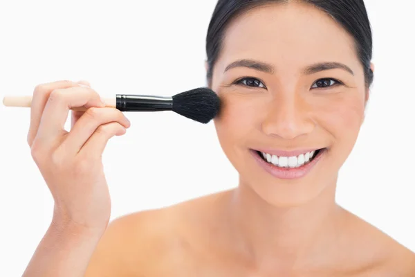 Cheerful dark haired model applying powder on her face — Stock Photo, Image