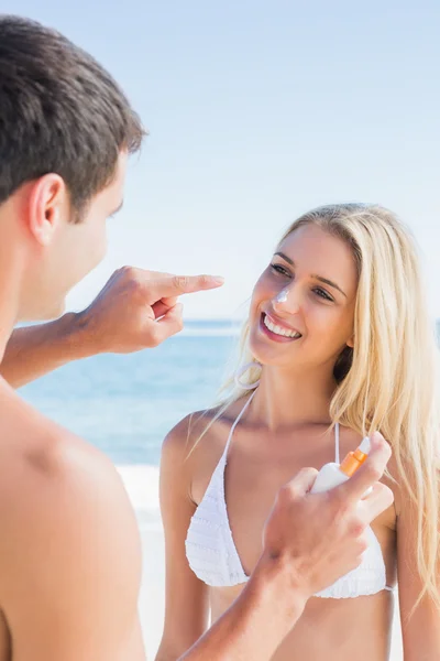 Mann setzt Sonnencreme auf süße Freundinnen Nase — Stockfoto