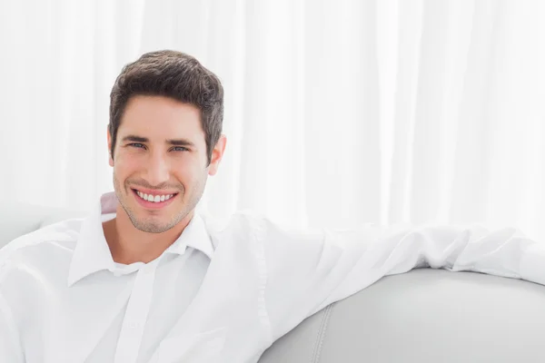 Guapo joven sentado en el sofá — Foto de Stock