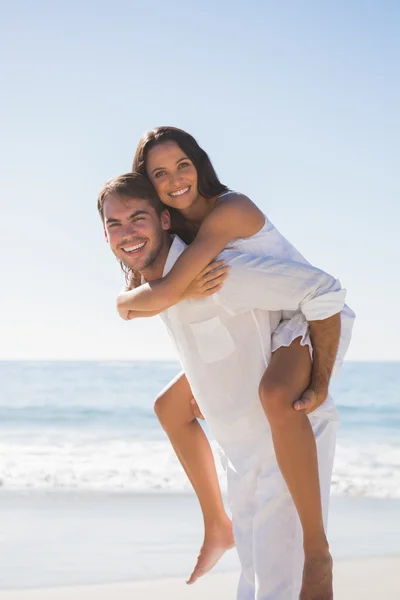 Usmívající se muž dává radost přítelkyni prasátko zpět — Stock fotografie
