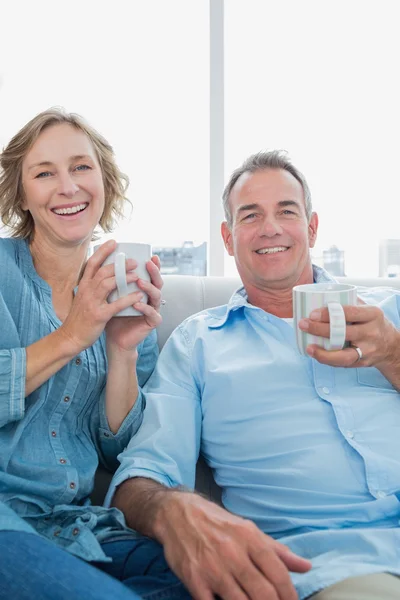 Feliz casal de meia-idade sentado no sofá tomando café — Fotografia de Stock