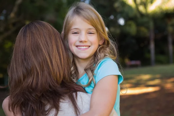 Menina sorrindo para a câmera realizada por sua mãe — Fotografia de Stock