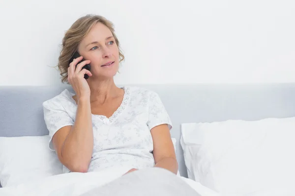 Mujer rubia en el teléfono en la cama — Foto de Stock