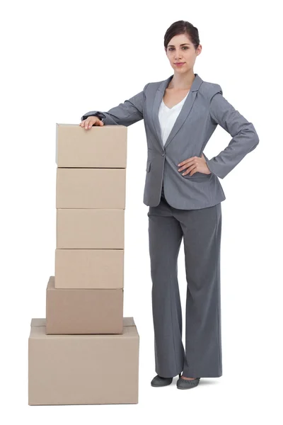 Serious businesswoman posing with cardboard boxes — Stock Photo, Image