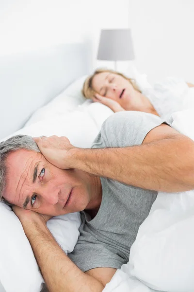 Geïrriteerde man blokkeren zijn oren van lawaai van vrouw snurken — Stockfoto