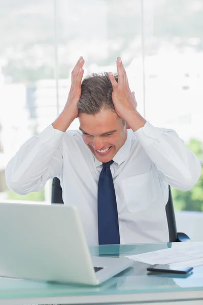 Boos zakenman handen op zijn hoofd kijken naar zijn laptop — Stockfoto