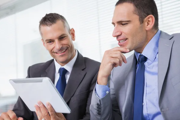 Lächelnde Geschäftsleute arbeiten gemeinsam an ihrem Tablet — Stockfoto