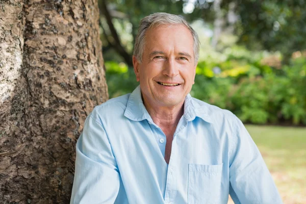 Happy retired man sitting on tree trunk — Stock Photo, Image