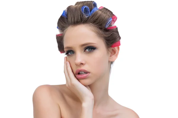 Pensive jovem mulher em encrespadores de cabelo posando e olhando para a câmera — Fotografia de Stock