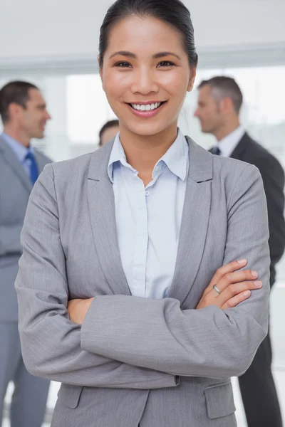 Empresária posando enquanto colegas conversando juntos — Fotografia de Stock