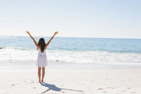 Morena en vestido de sol blanco de pie junto al agua con brazos rais —  Fotos de Stock