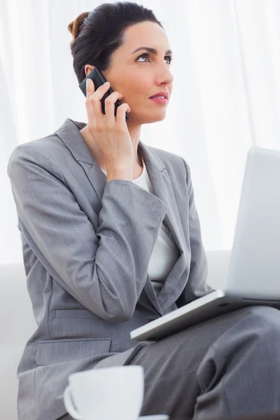 Businesswoman calling with her mobile phone and using laptop sit — Stock Photo, Image