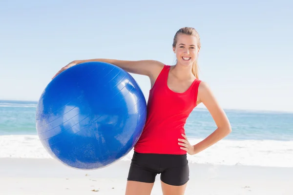 Fitte Blondine hält Übungsball lächelnd in die Kamera — Stockfoto