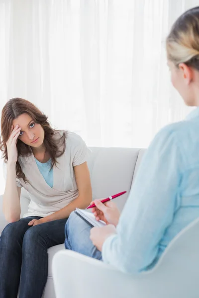 Bezorgd vrouw zitten met therapeut het maken van notities — Stockfoto