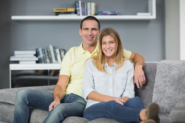 Attractive young couple sitting on their couch — Stock Photo, Image