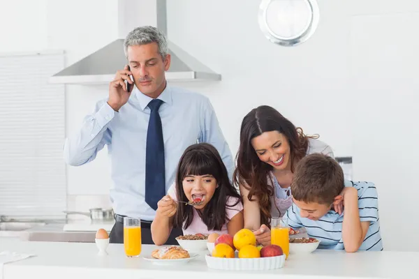 Far ringa med mobiltelefon med sin familj äta breakfas — Stockfoto