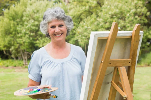 Happy mature woman painting on canvas — Stock Photo, Image