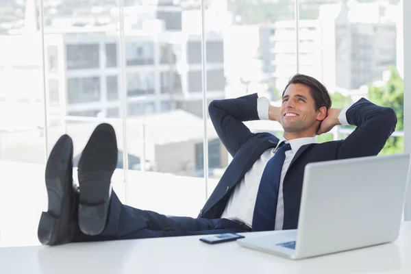 Успешный бизнесмен расслабляется с ногами на столе — стоковое фото