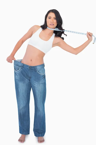 Sexy woman wearing too big pants and strangling herself with mea — Stock Photo, Image