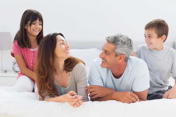 Lächelnde Familie beim gemeinsamen Gespräch im Bett — Stockfoto