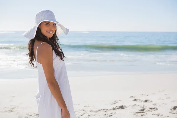 Brunette in white sunhat looking over her shoulder at camera — Zdjęcie stockowe