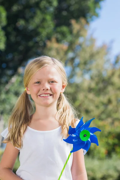 Nettes blondes Mädchen mit Windrad lächelt in die Kamera — Stockfoto