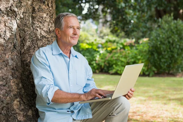 Volwassen man met een laptop op zoek naar de hemel — Stockfoto