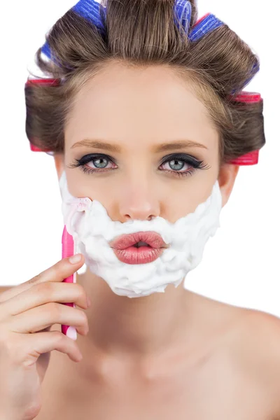 Sexy young model in hair curlers posing with razor — Stock Photo, Image