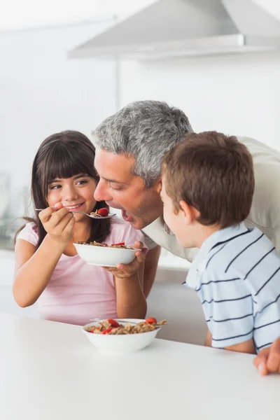 Siblings sharing cereal with their father — Stock Photo, Image