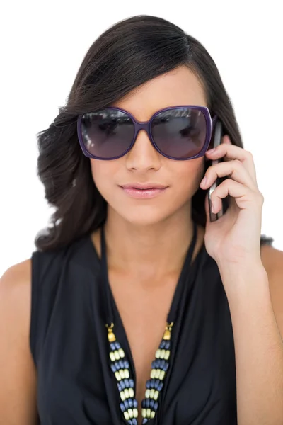 Elegant brunett bär solglasögon på telefonen — Stockfoto