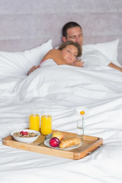 Attractive couple asleep with breakfast tray on bed — Stock Photo, Image