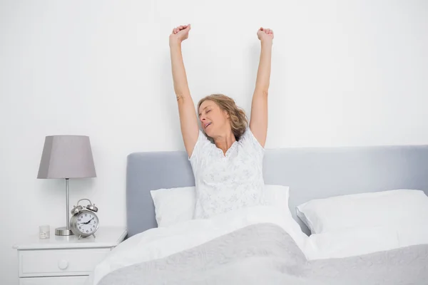 Well rested blonde woman stretching after waking up in bed — Stock Photo, Image