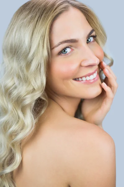 Uśmiechający się przepiękny blond modelu pozowanie podczas dotykania twarzy — Zdjęcie stockowe