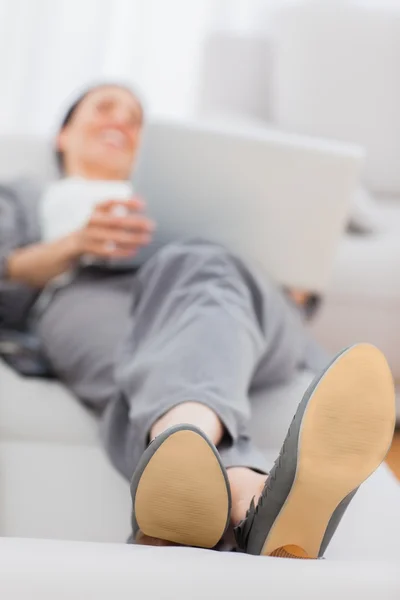 Mujer de negocios acostada en el sofá con su portátil — Foto de Stock