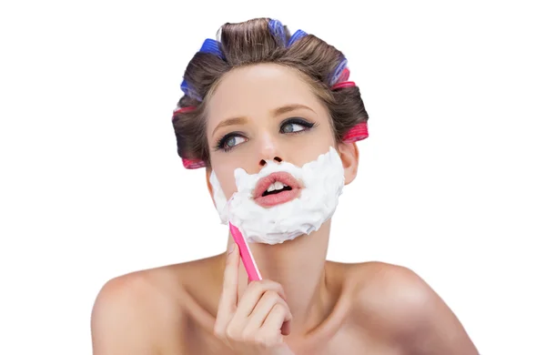 Femme pensive dans les bigoudis posant avec rasoir — Photo