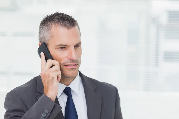 Homem de negócios concentrado posando enquanto tem um telefonema — Fotografia de Stock