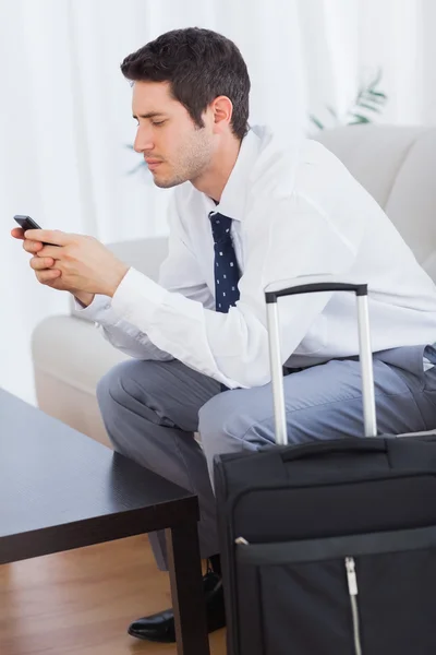 Empresario con su maleta usando teléfono móvil — Foto de Stock