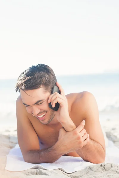 Souriant bel homme sur la plage au téléphone — Photo