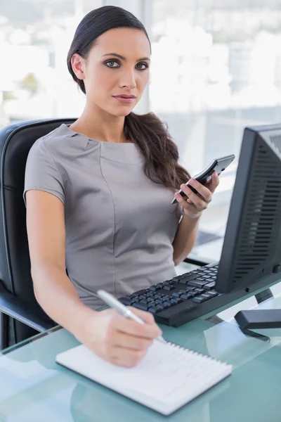 Sexy businesswoman using calculator and writing — Stock Photo, Image