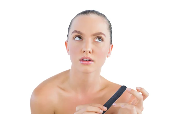 Thoughtful brunette with nail file — Stock Photo, Image