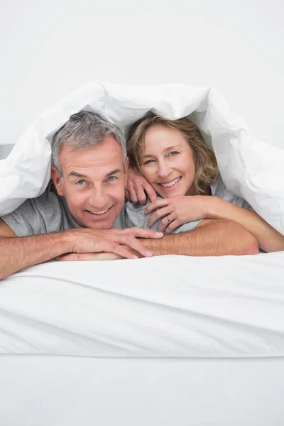 Fröhliches Paar mittleren Alters unter der Bettdecke — Stockfoto