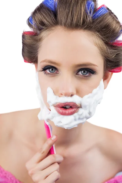 Young model in hair curlers posing with razor — Stock Photo, Image