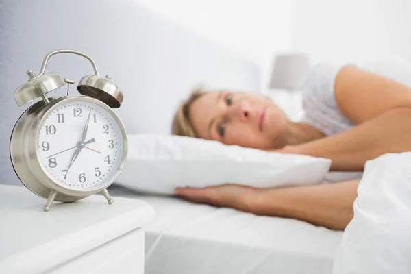 Femme blonde couchée au lit tandis que son alarme montre les premiers temps — Photo