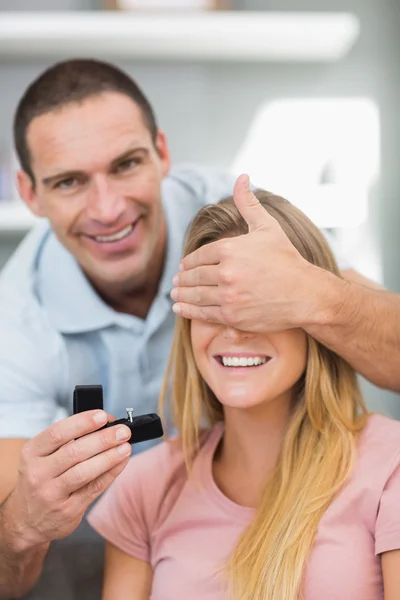 Man about to propose to his unsuspecting girlfriend on the sofa — Stock Photo, Image